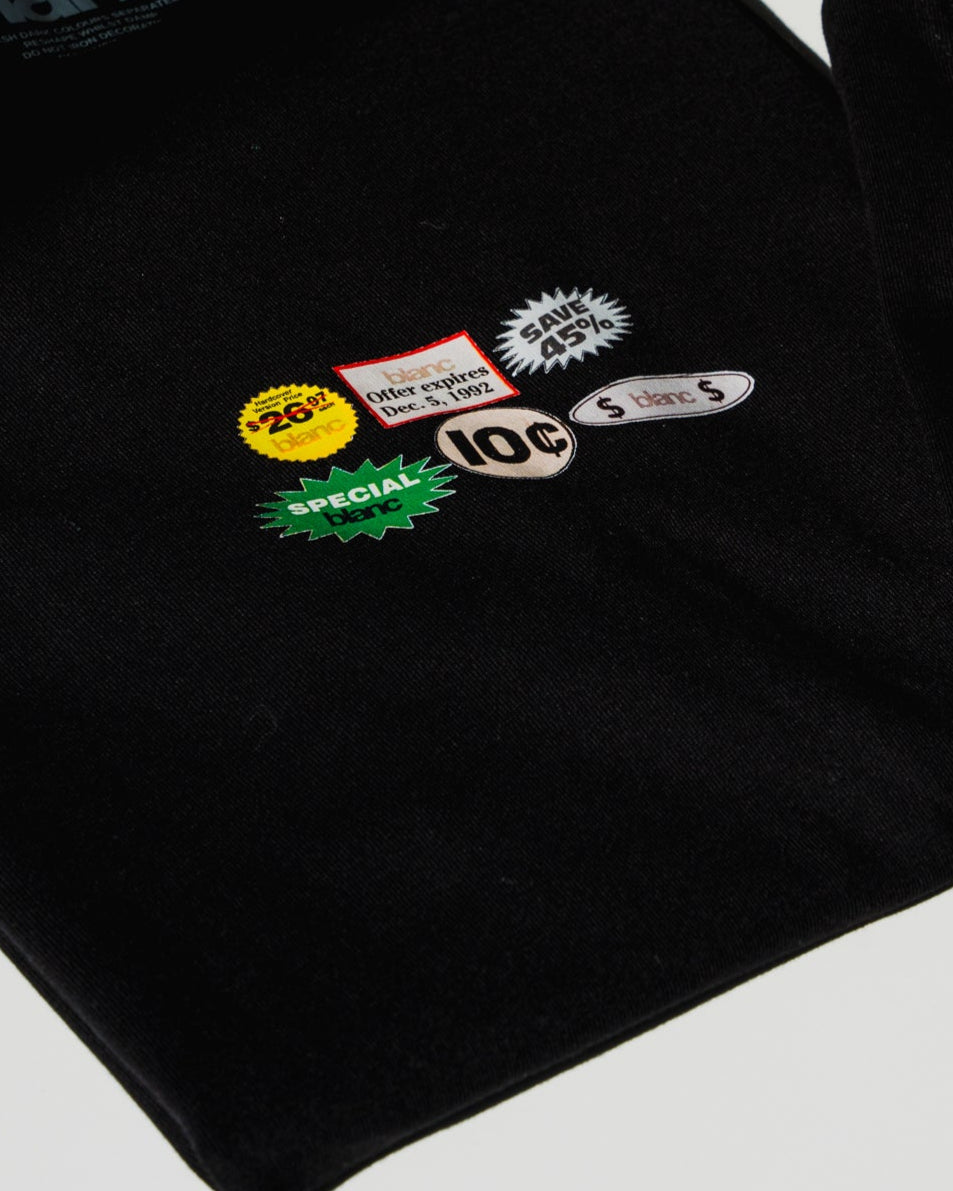 Black blanc t-shiry with vintage-style store stickers on a light gray background
